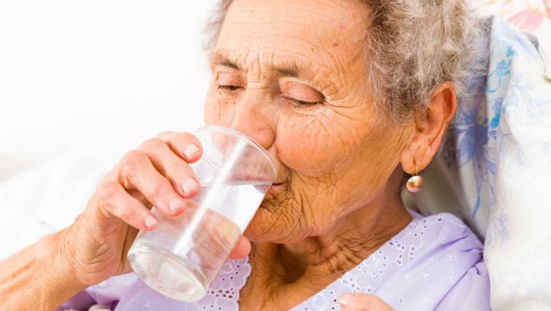 Elderly woman drinking water and self medicating